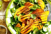 Barbecued pumpkin wedges on spinach salad